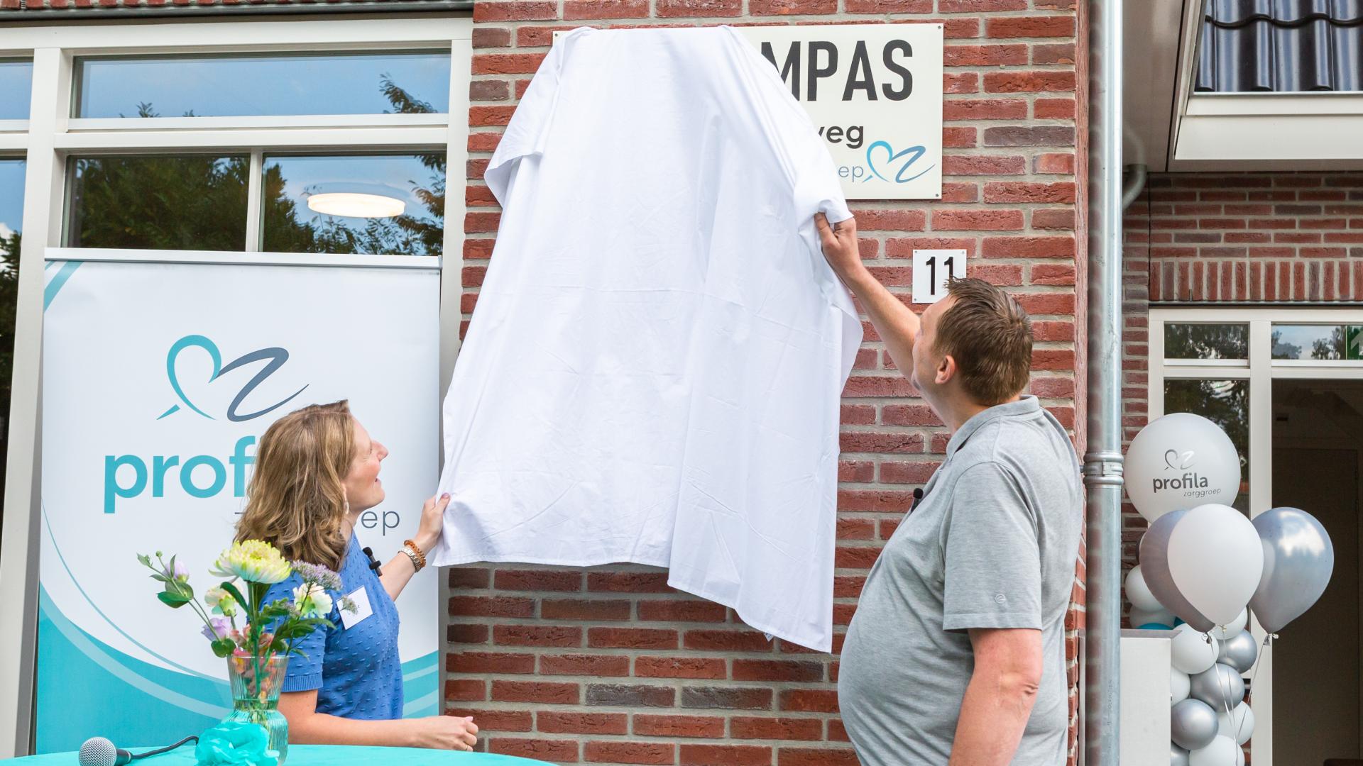 Teamleider Elise de Roover en bewoner Jan Tol onthullen de naam van de nieuwe woning